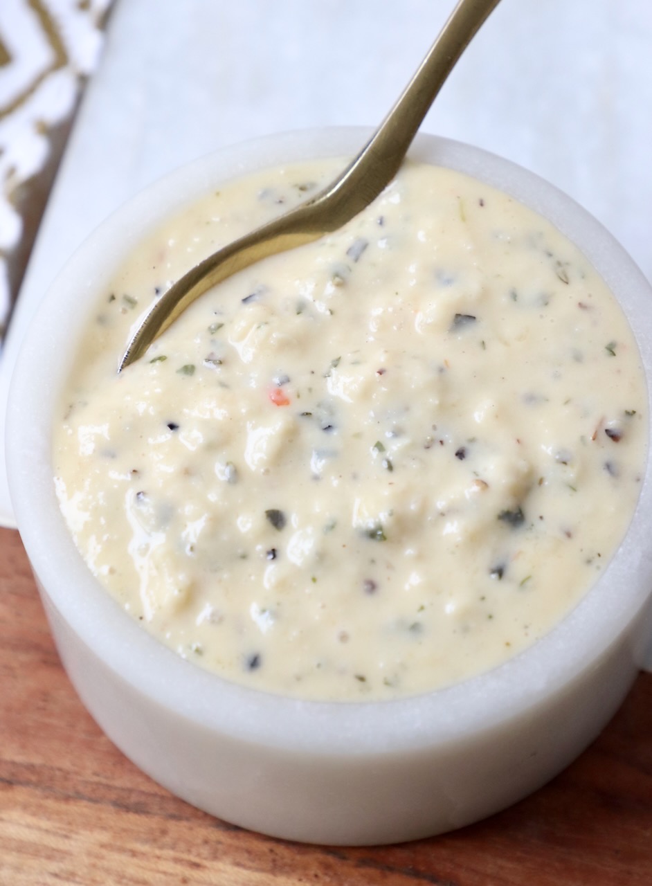 garlic parmesan sauce in small bowl with gold spoon