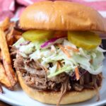pulled pork sandwich on a plate with french fries
