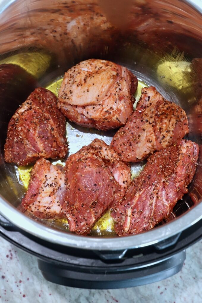 large pieces of seasoned pork in olive oil in Instant Pot