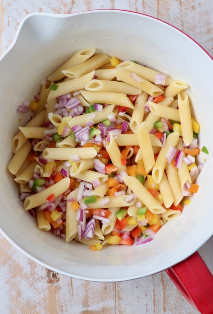 cooked penne pasta and diced vegetables in large mixing bowl