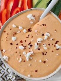 roasted red pepper feta dip in bowl topped with feta cheese crumbles and red pepper flakes