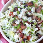 chopped salad in bowl topped with blue cheese and bacon