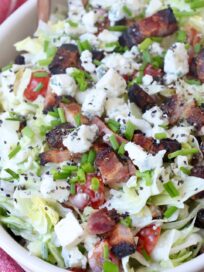 chopped salad in bowl topped with blue cheese and bacon