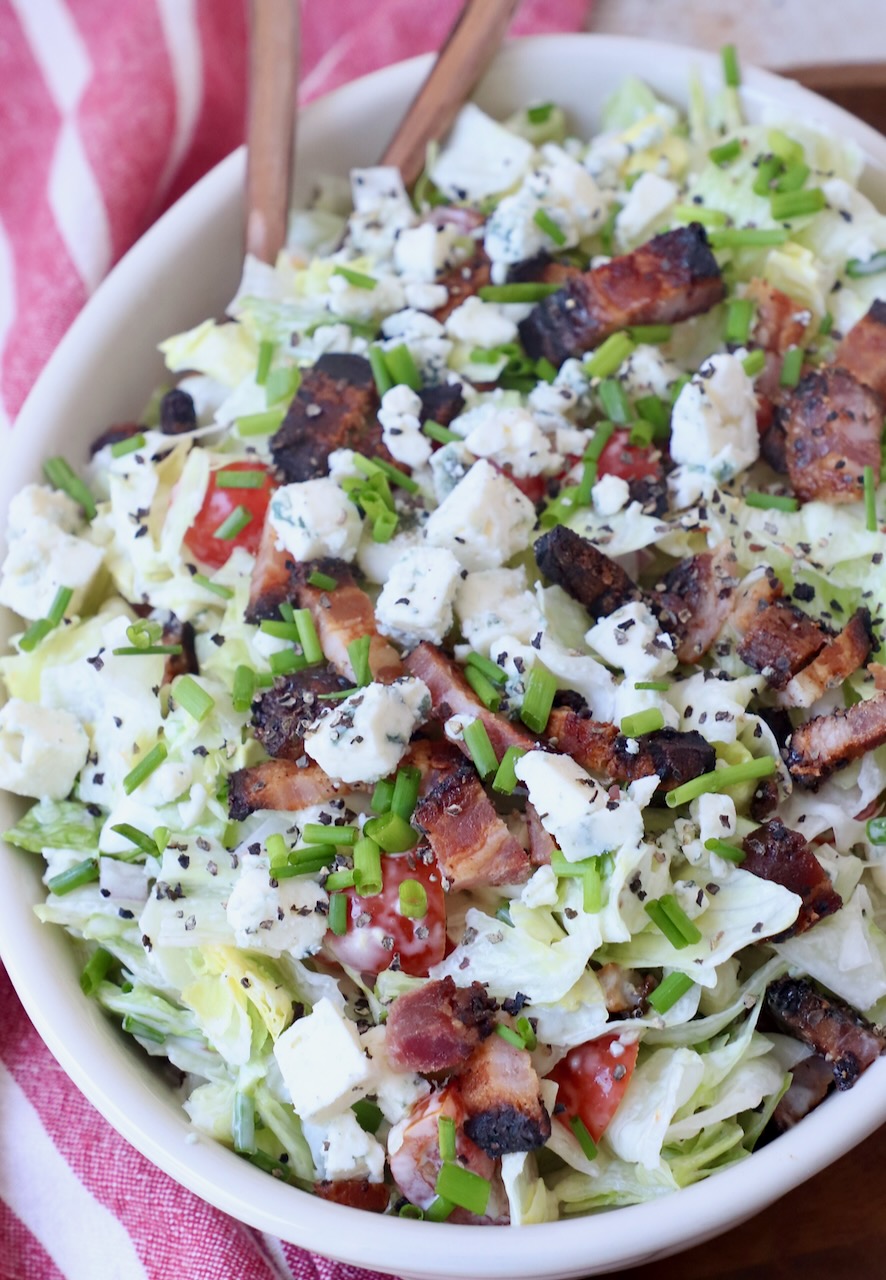 chopped blue cheese salad topped with chopped bacon in bowl with spoon