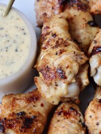 grilled chicken wings on plate with a small bowl of garlic parmesan sauce on the side