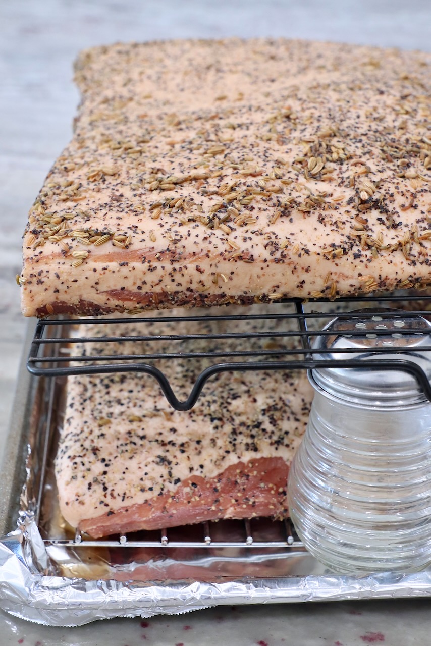 seasoned pork belly on wire rack on top of foil lined baking sheet