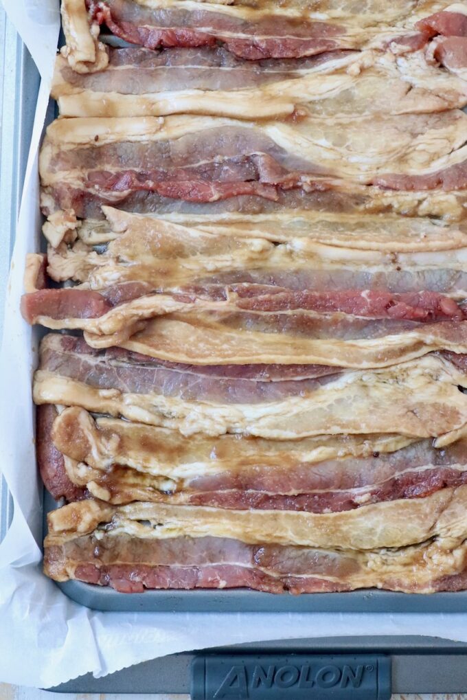 uncooked strips of bacon on wire rack on top of foil lined baking sheet
