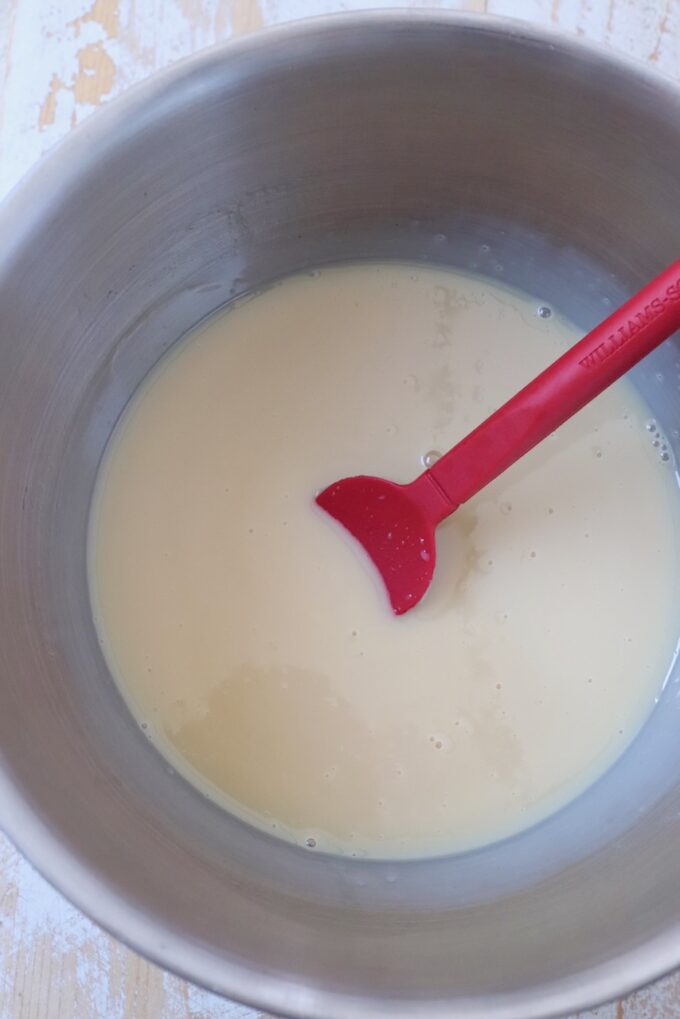 sweetened condensed milk in bowl with red spatula