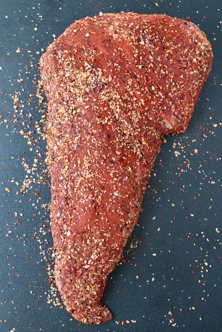 seasoned uncooked tri tip roast on cutting board