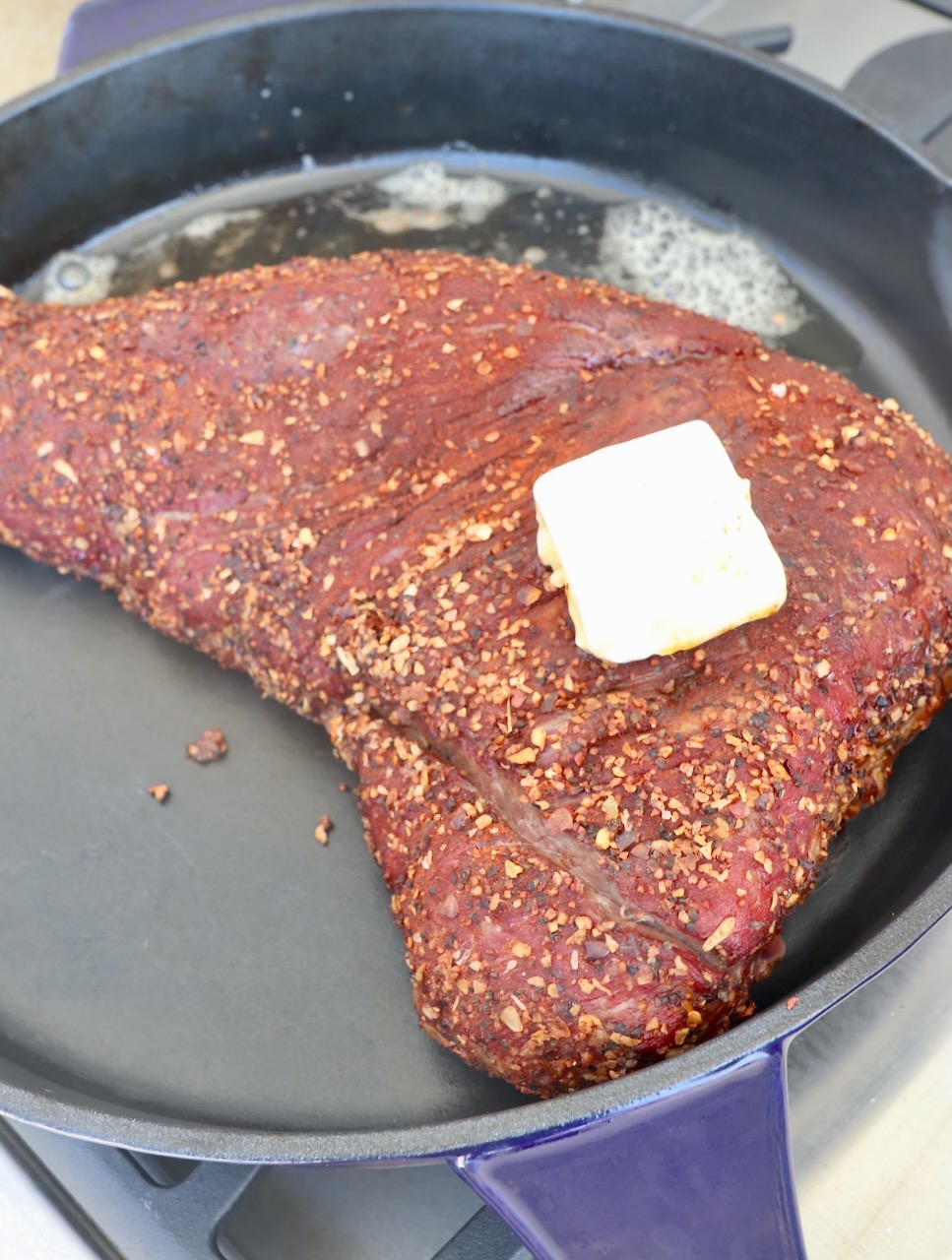smoked seasoned tri tip in cast iron skillet topped with butter