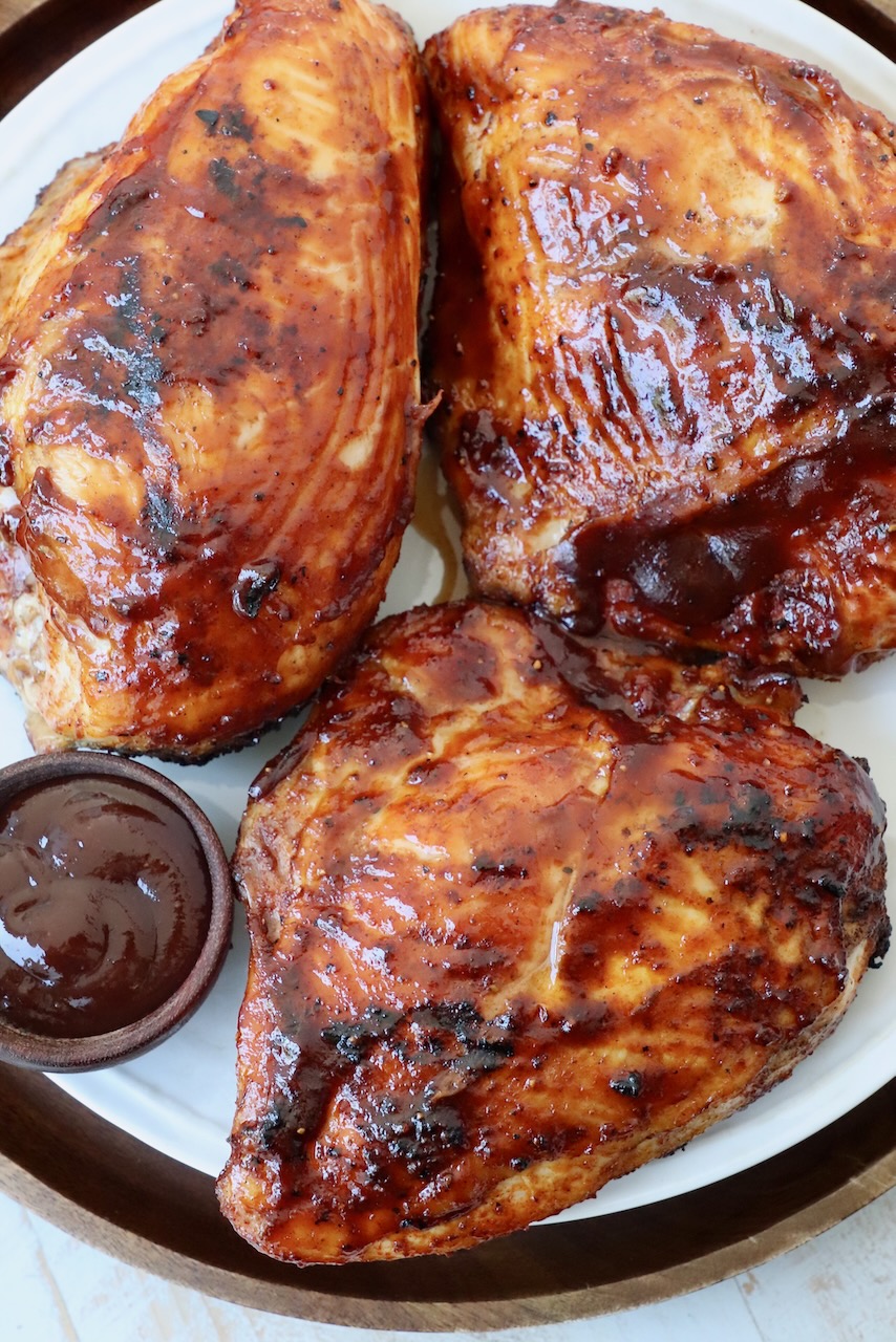 grilled chicken breasts on plate covered with bbq sauce
