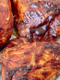 grilled bbq chicken breasts on plate coated with bbq sauce