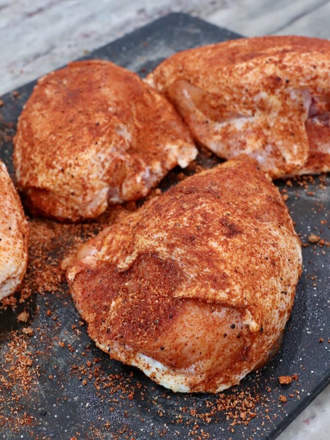 seasoned bone-in chicken breasts on cutting board