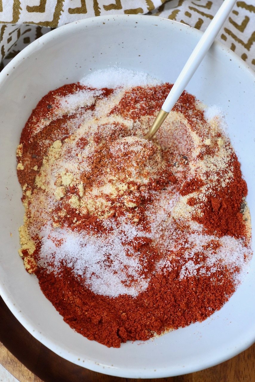 spices mixed together in a bowl with a small spoon
