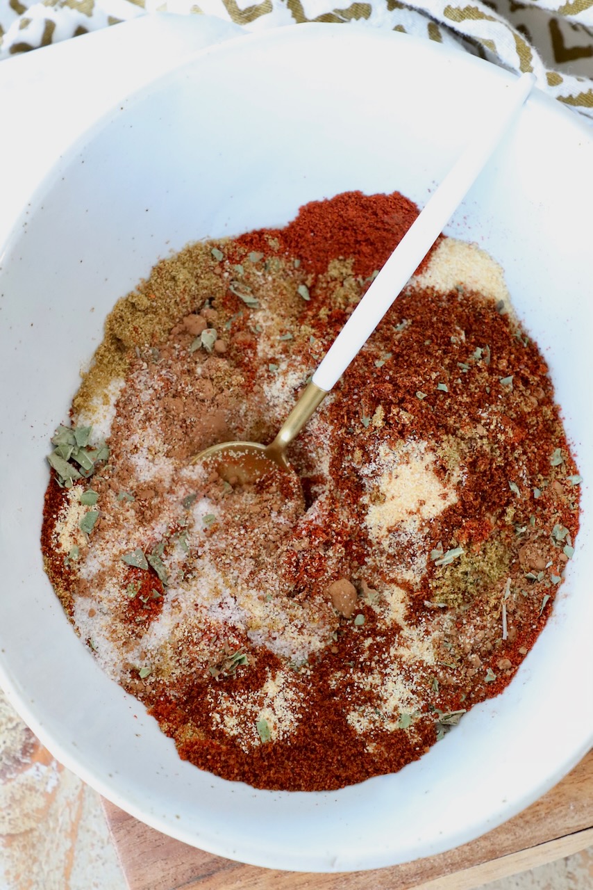 spices and herbs mixed together in a bowl with spoon