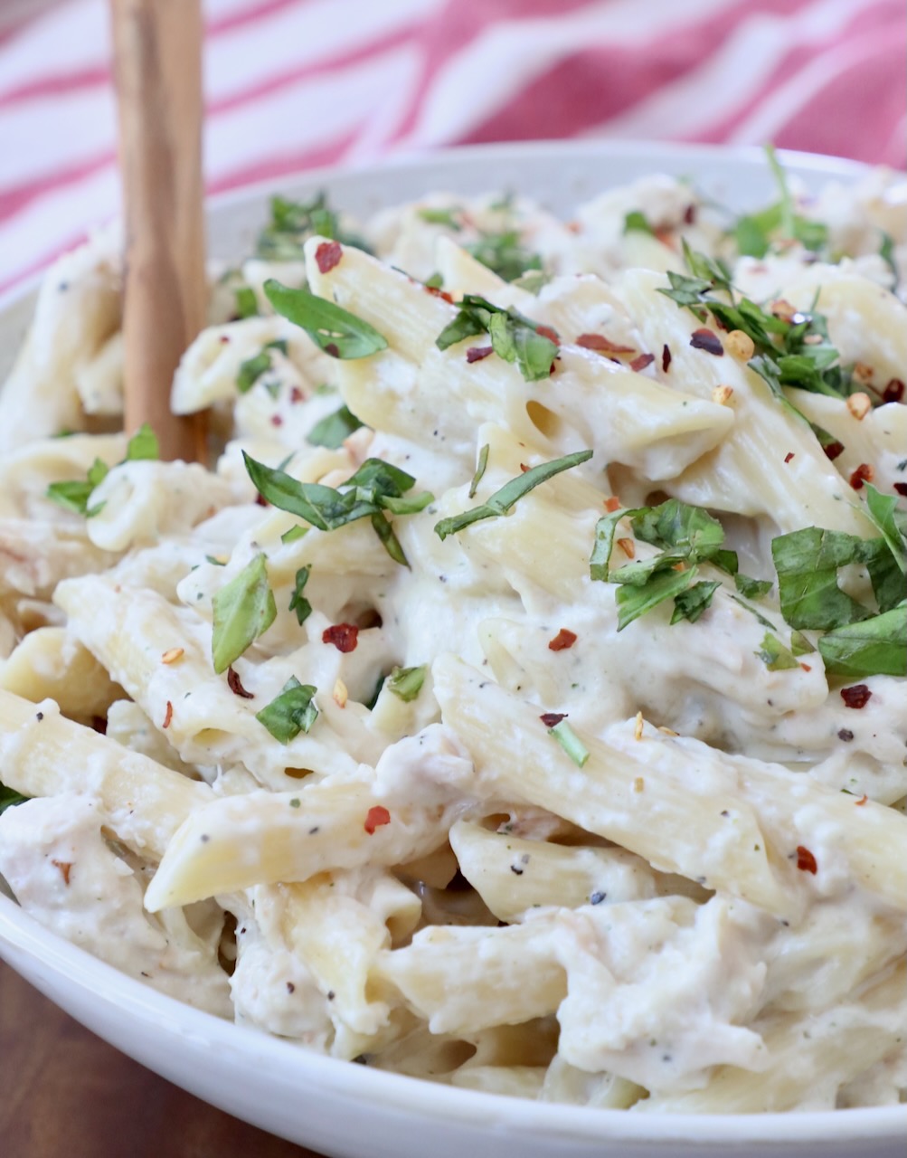 pasta tossed with creamy sauce in bowl with serving spoon