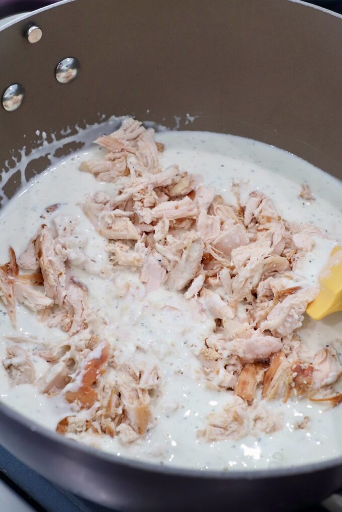 cooked, shredded chicken in pan with white sauce