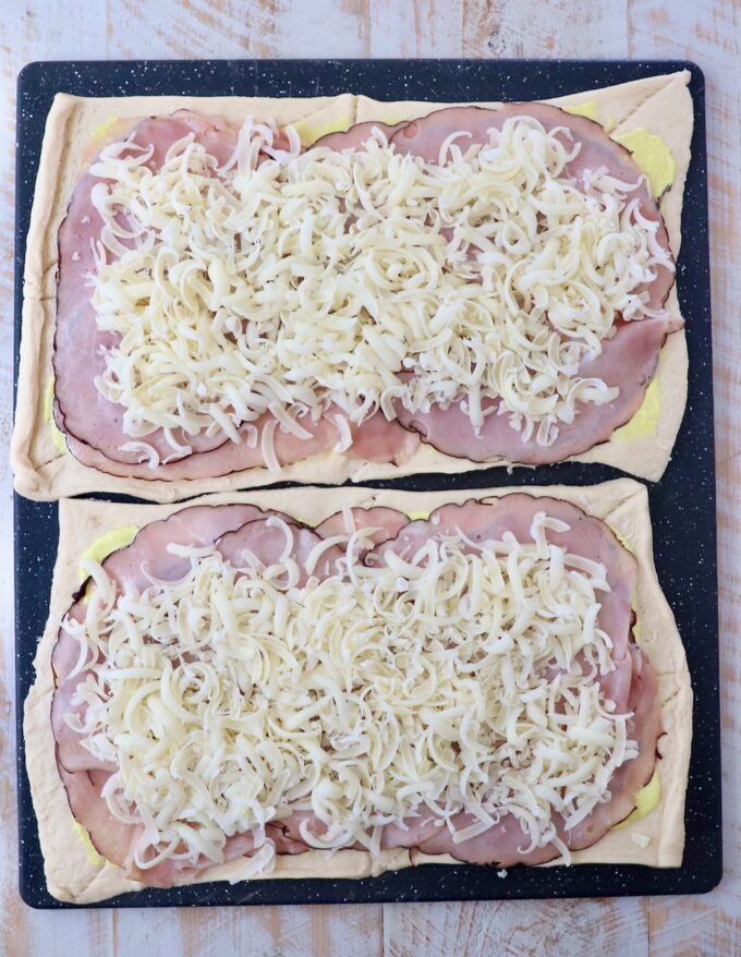 crescent roll dough sheets topped with sliced ham and shredded swiss cheese