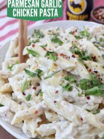creamy chicken pasta in bowl topped with fresh chopped basil, with serving spoon in the bowl