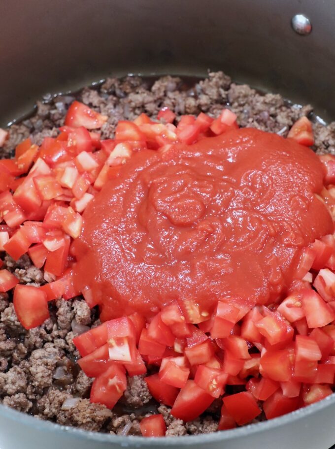 cooked ground beef with diced tomatoes and tomato sauce in large skillet