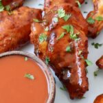 smoked chicken wings on plate tossed with buffalo sauce