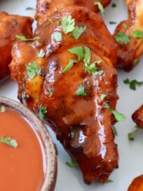 smoked chicken wings tossed in buffalo sauce on plate