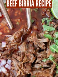 shredded beef in birria broth in a bowl with forks