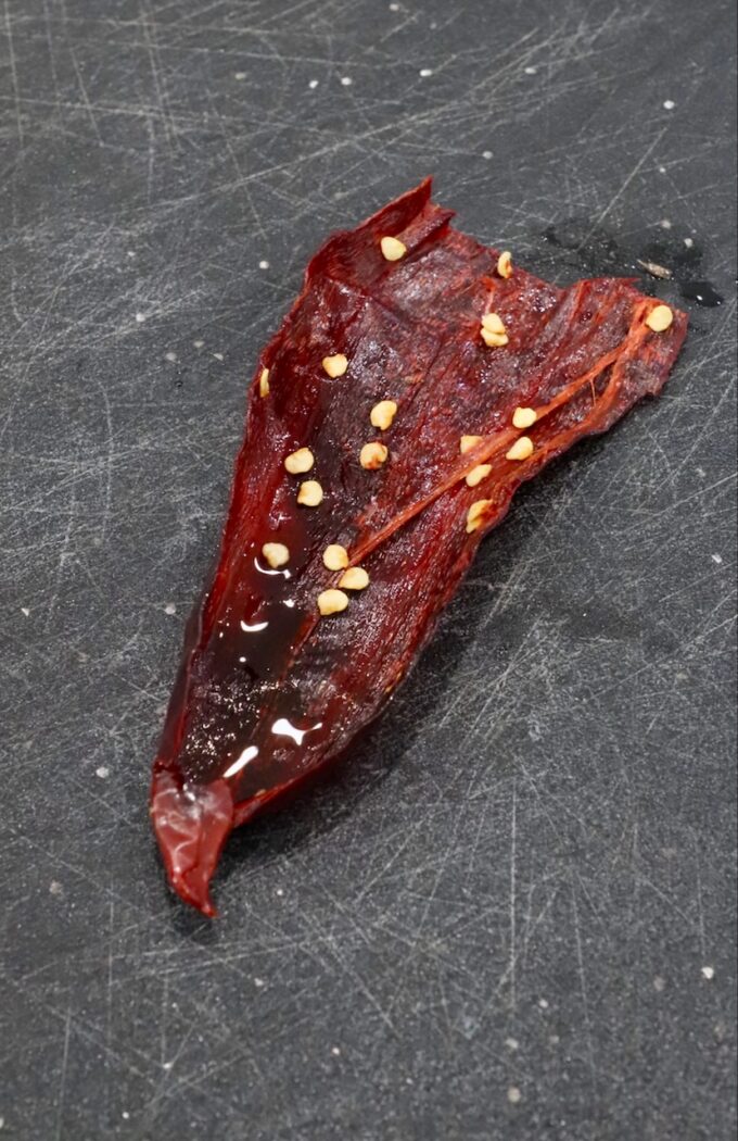 dried chili pepper cut open on cutting board