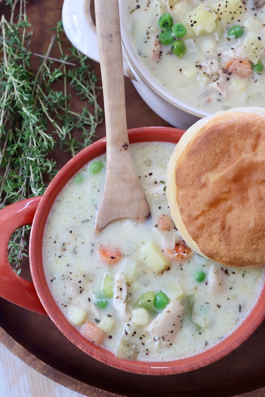 chicken pot pie soup in bowls, topped with a biscuit