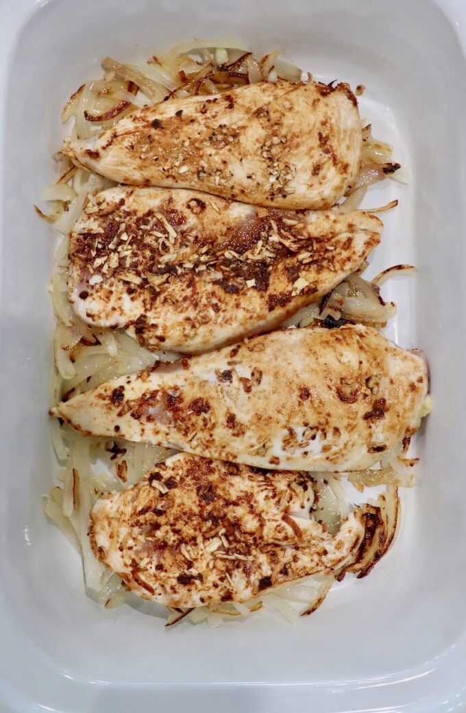 seasoned, seared chicken breasts in slow cooker with caramelized onions