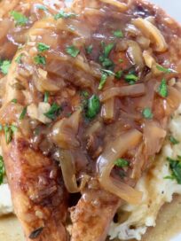 cooked chicken breasts on plate with caramelized onion gravy