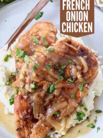 cooked chicken breasts on plate with caramelized onion gravy and mashed potatoes