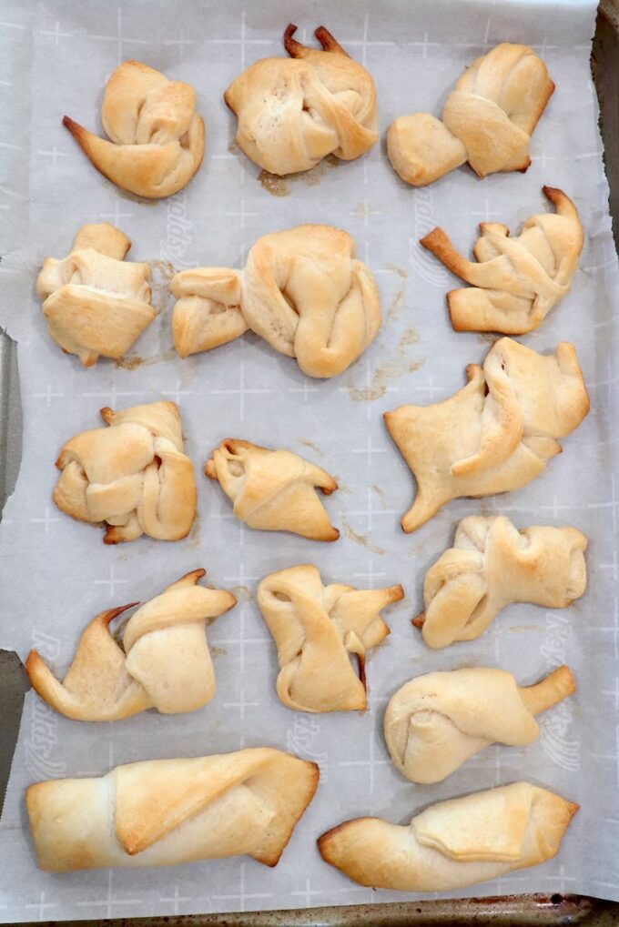 baked crescent roll dough scraps tied together on parchment-lined baking sheet