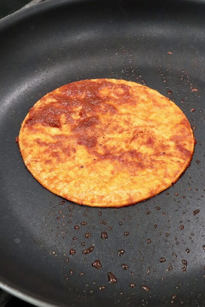 tortilla covered in sauce in skillet