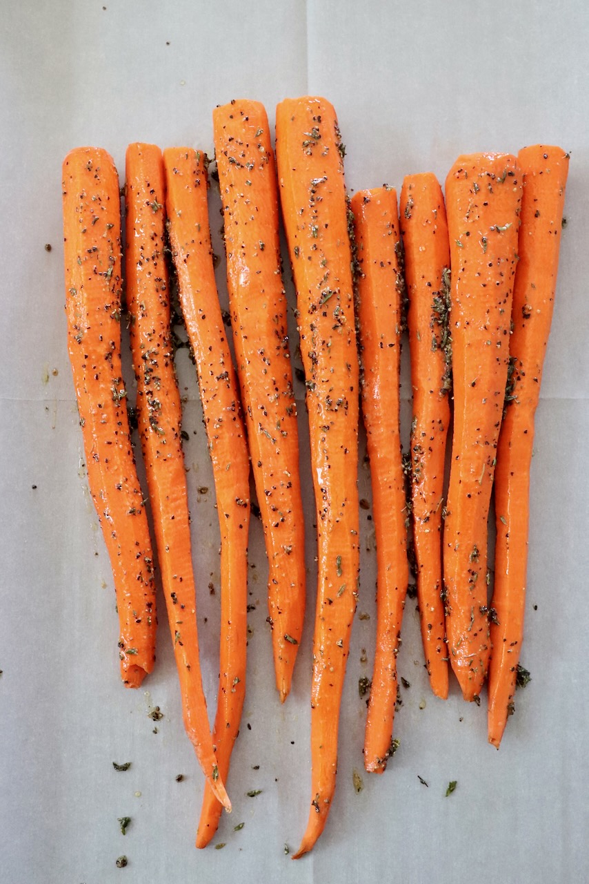 seasoned carrots on parchment lined baking sheet