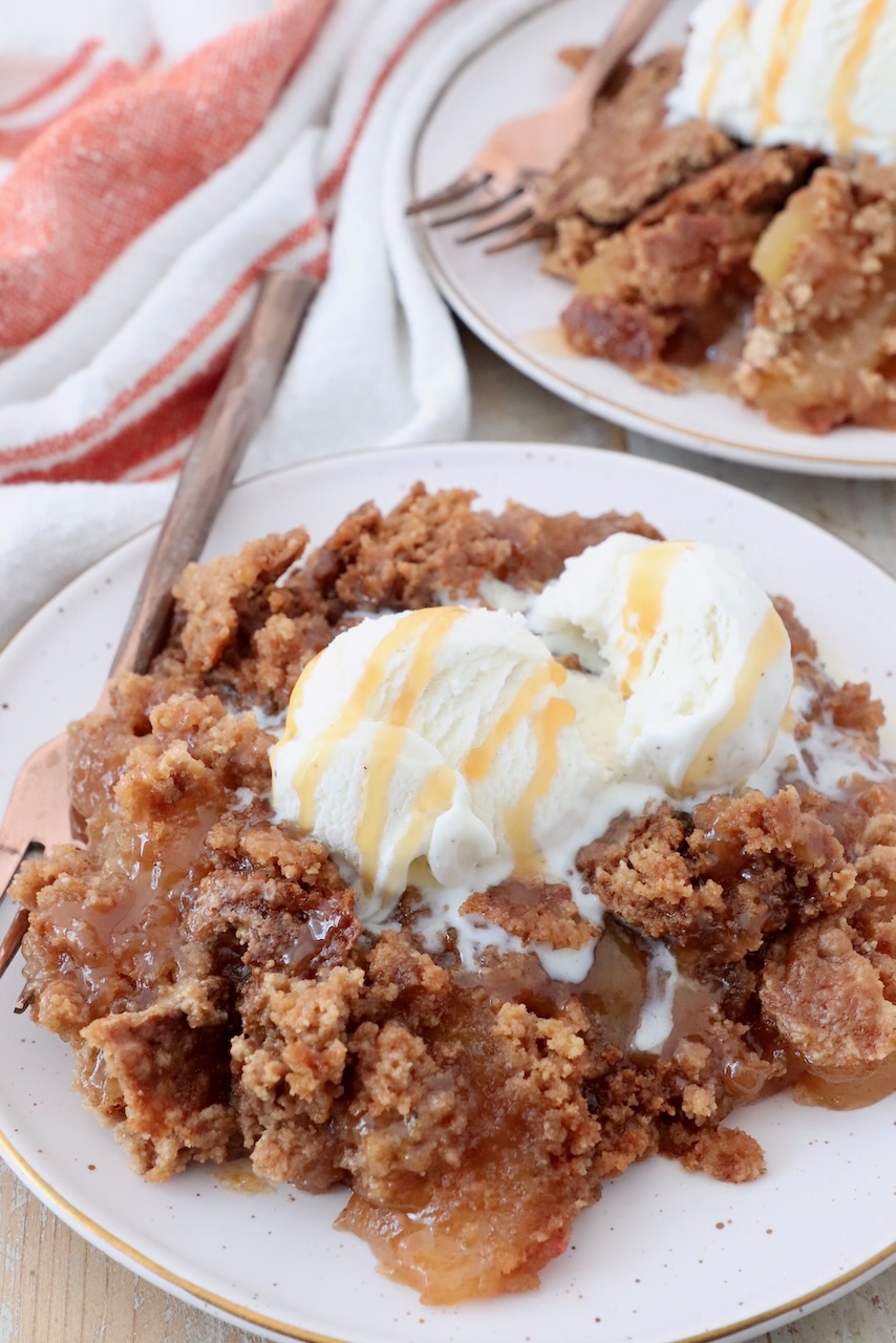 baked caramel apple dump cake on plate with scoop of ice cream on top