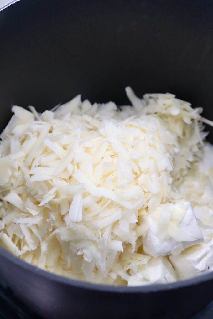 shredded provolone and cubed cream cheese in pot