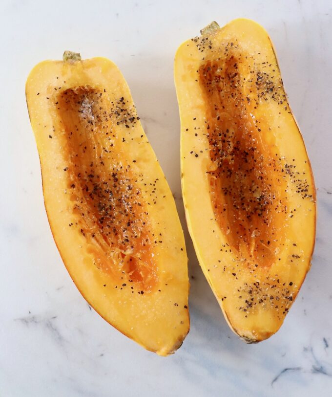 delicata squash cut in half with the seeds removed and seasoned with salt and pepper