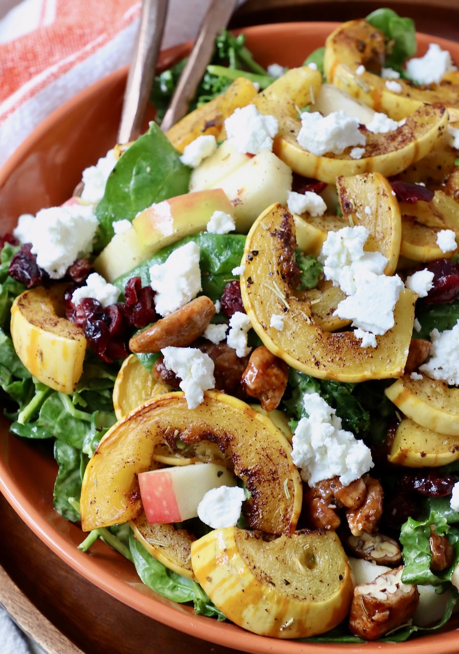 roasted sliced delicata squash on top of salad in bowl