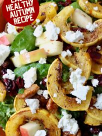 salad in bowl topped with roasted strips of delicata squash and crumbled goat cheese