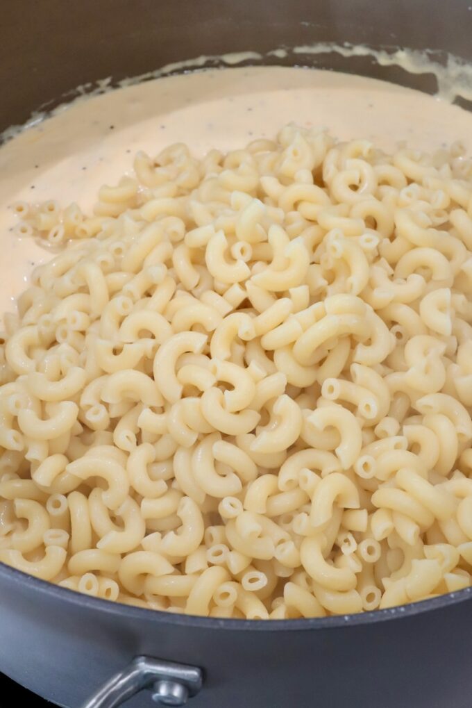 cheese sauce topped with cooked macaroni noodles in a large pot