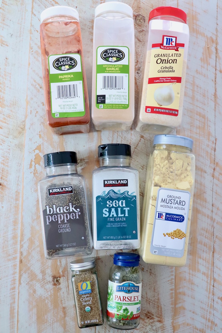 herbs and spices in plastic containers on white wood board