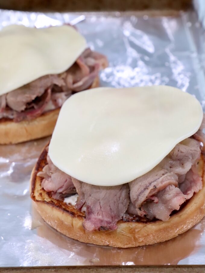 bun topped with roast beef and a slice of provolone cheese