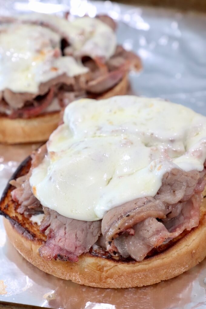 melted provolone cheese over roast beef on a bun