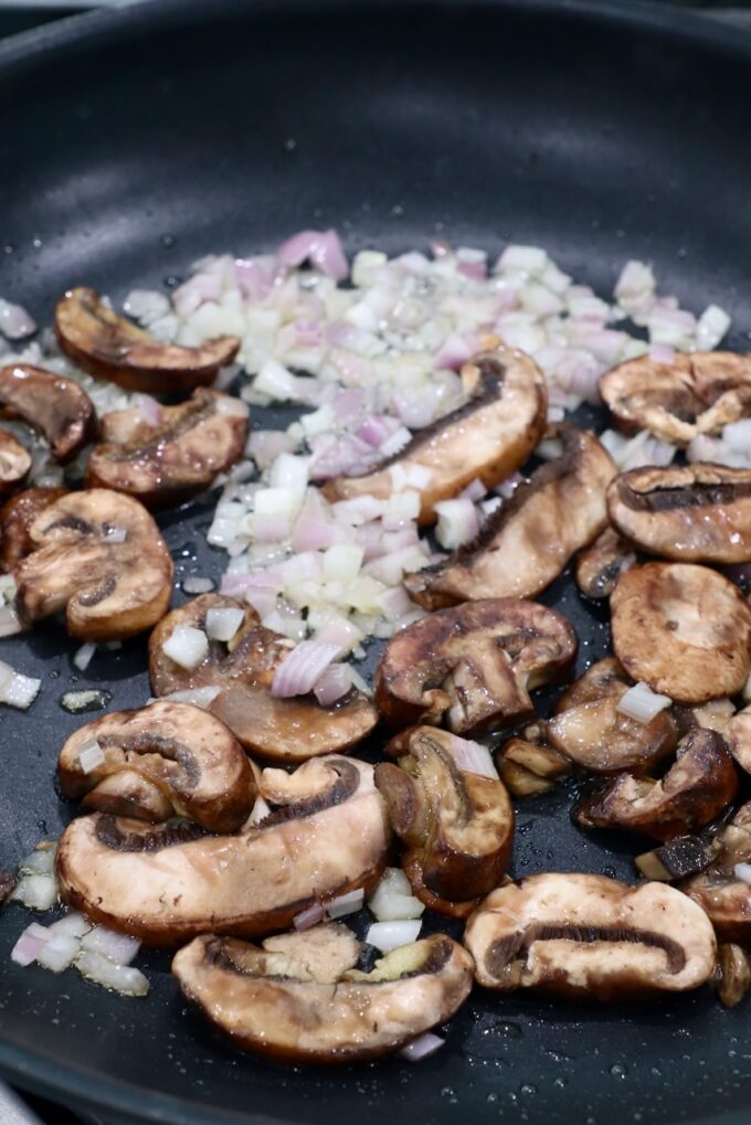 sliced mushrooms and diced shallots in a skillet