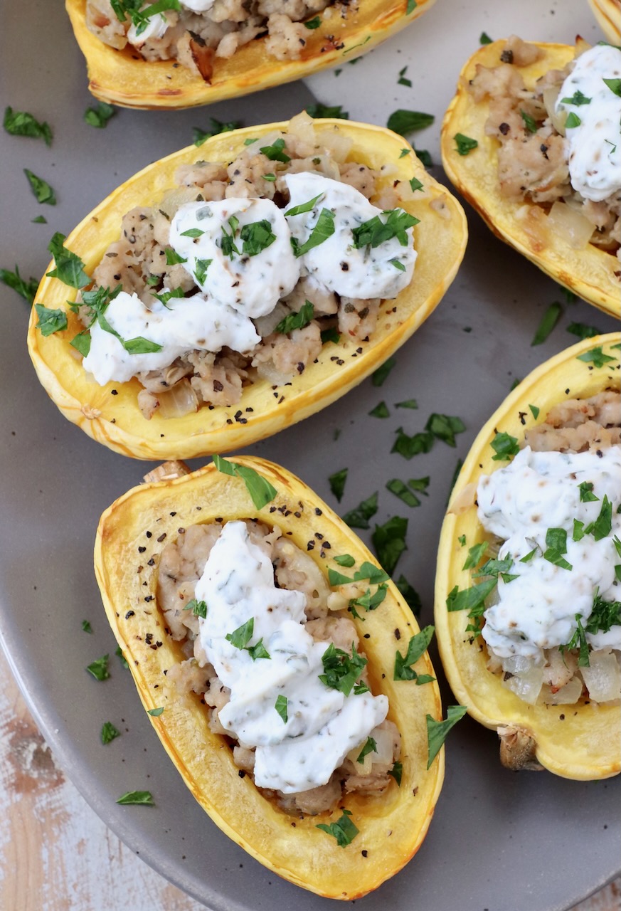 roasted delicata squash filled with cooked sausage and ricotta cheese on plate