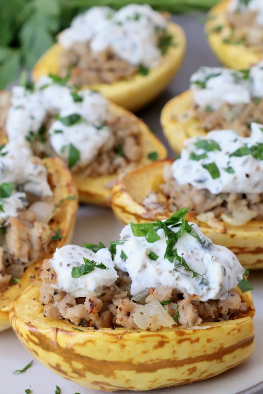 roasted delicata squash cut in half stuffed with ground chicken sausage and ricotta cheese on plate