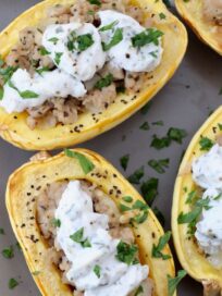 roasted delicata squash cut in half stuffed with cooked ground chicken sausage and ricotta cheese on plate