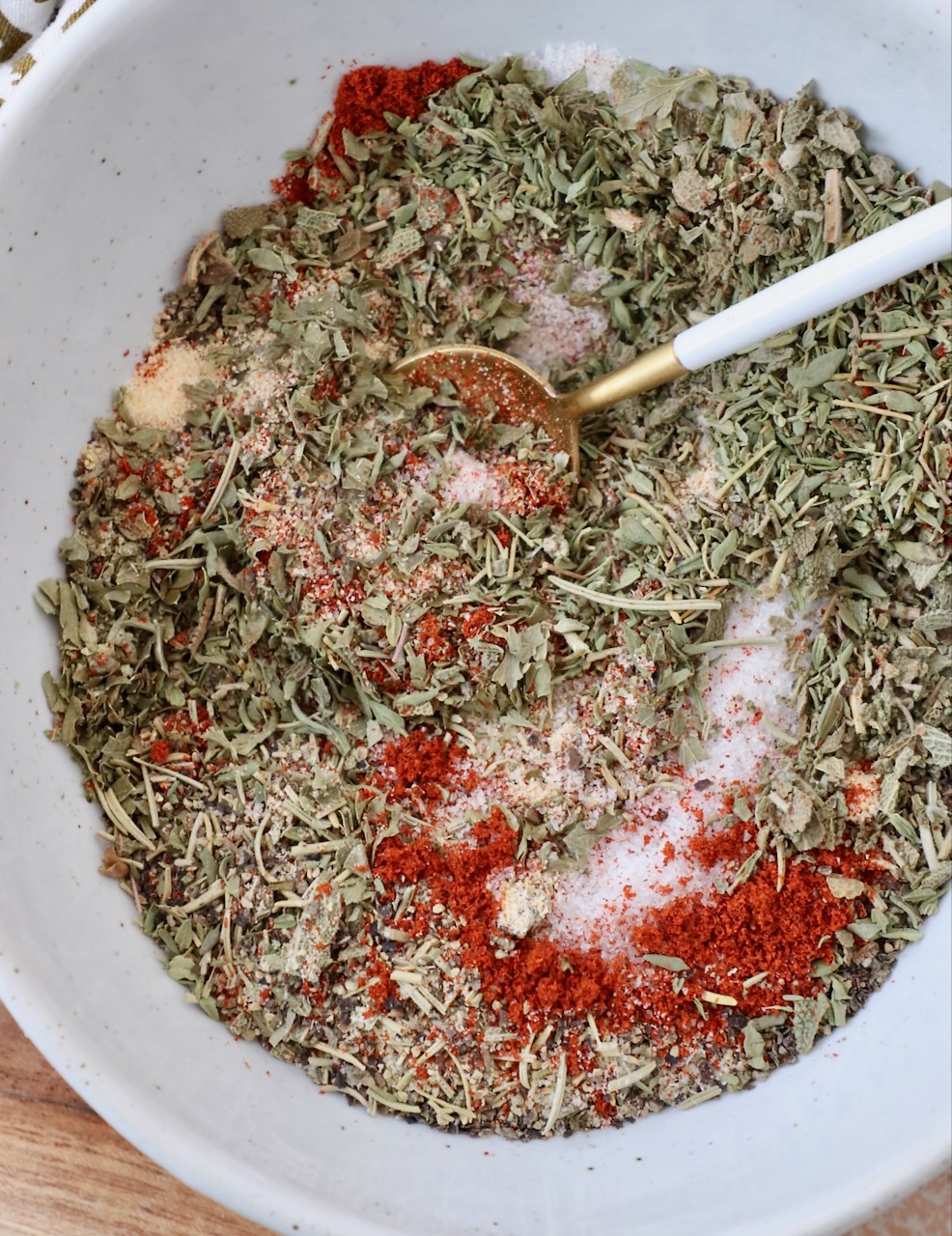 herbs and spices mixed together in bowl with a small spoon