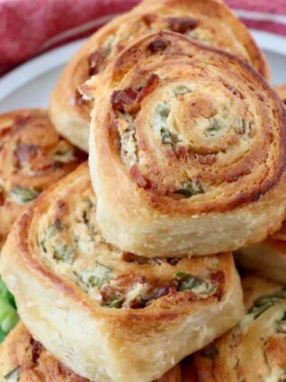 baked cheesy bacon crescent rolls stacked up on a plate